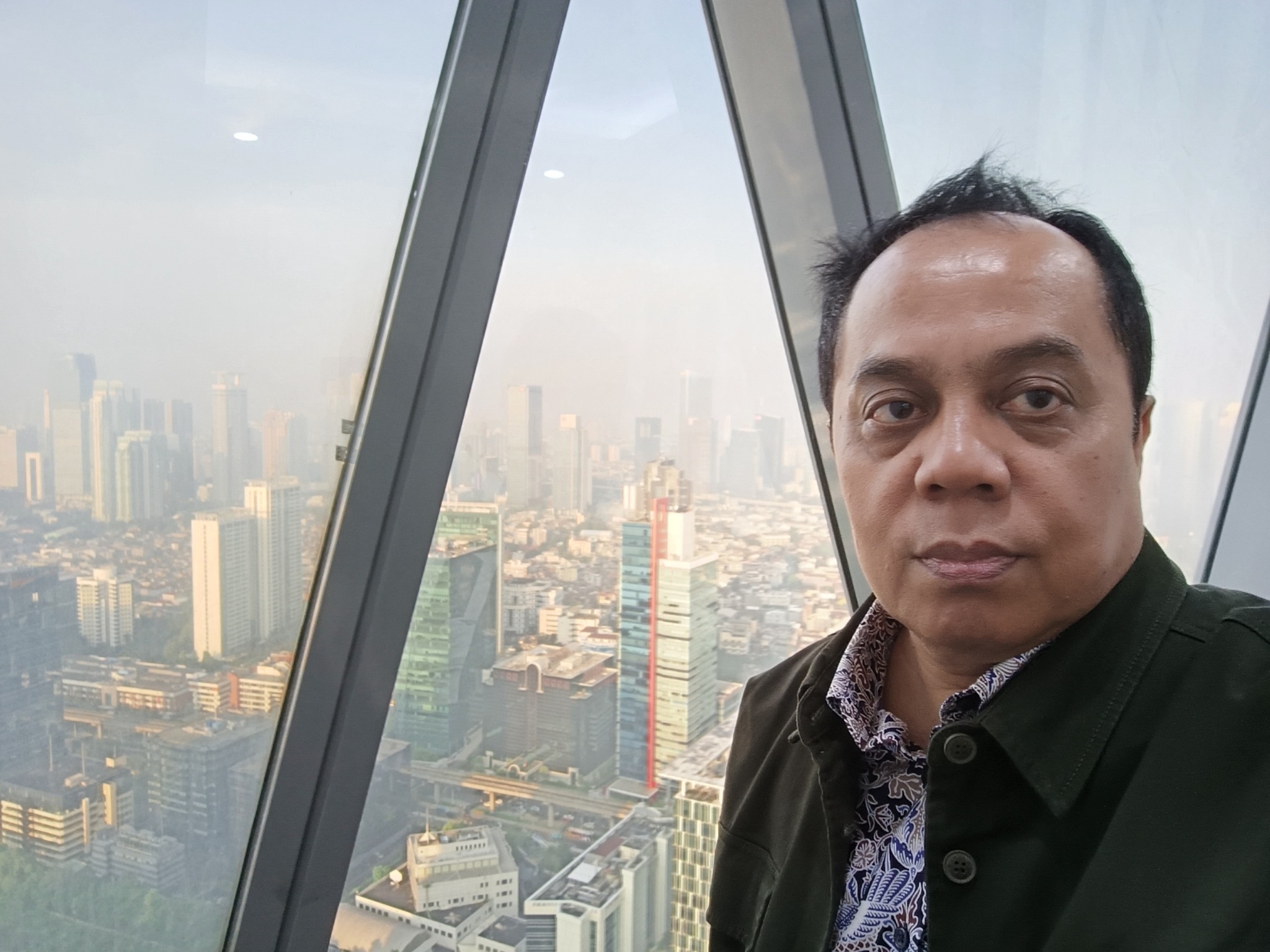 Dr. H. Benrahman dengan latar pemandangan Kota Jakarta dari ketinggian